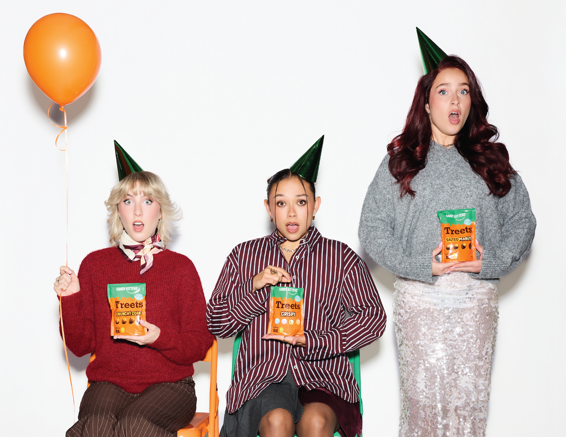 Three friends in party hats holding bags of Treets, including Crunchy Corn
